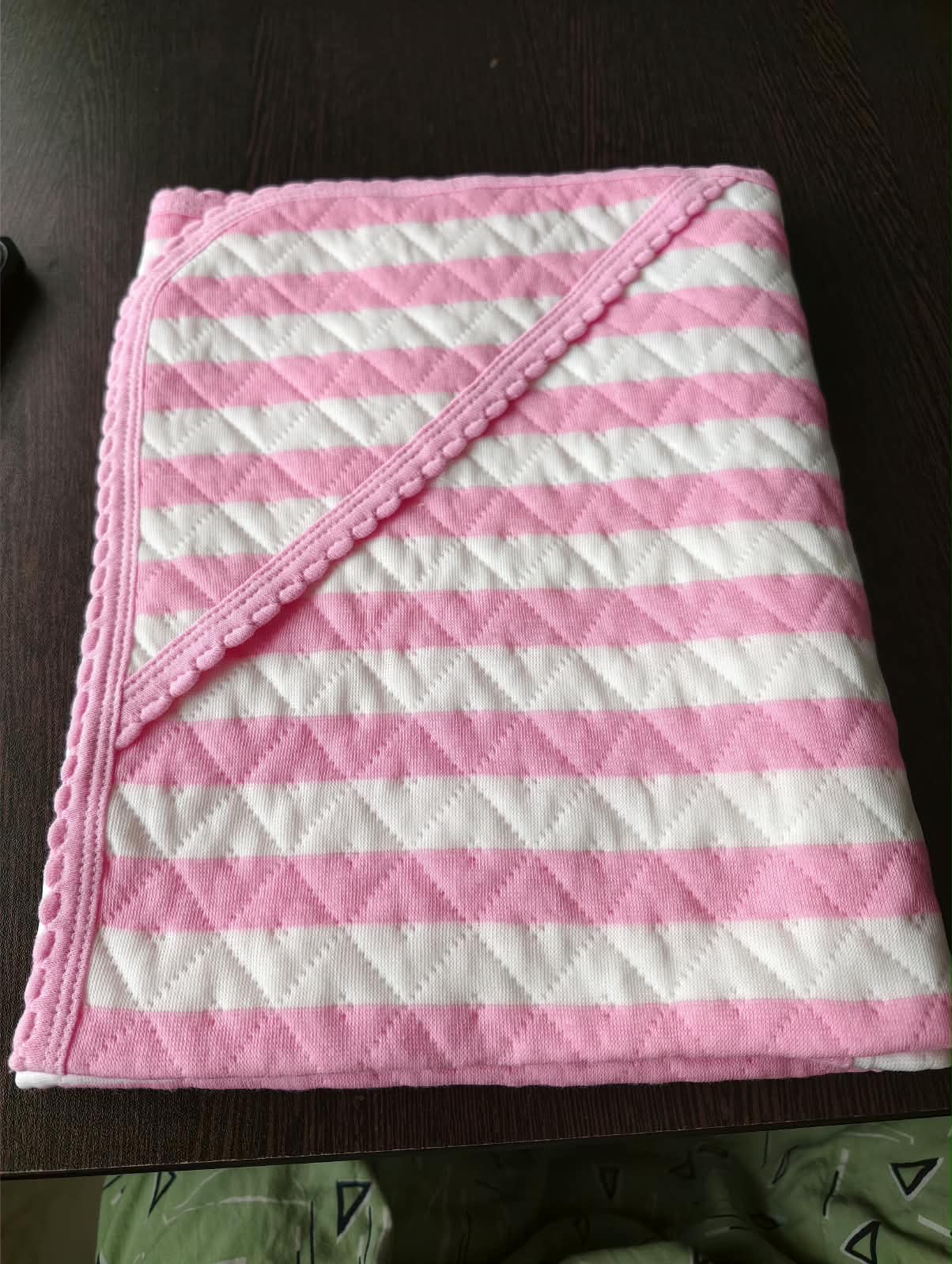 Pink and white striped baby wrap towel folded on a table